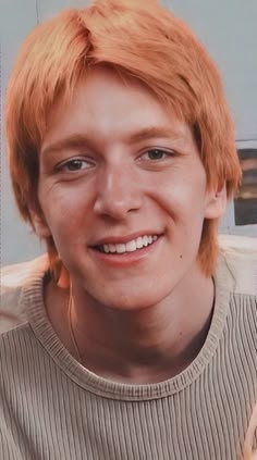 a young man with red hair smiling at the camera