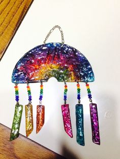 a multicolored wind chime hanging on a wooden table with beads and chains