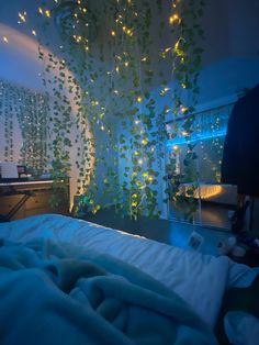 an unmade bed with lights hanging from the ceiling