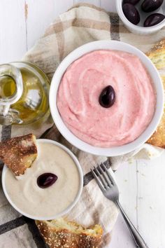 a bowl of hummus next to some olives and bread