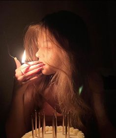 a woman blowing out the candles on her birthday cake