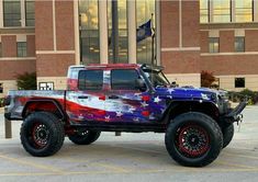 a jeep with an american flag paint job parked in front of a large brick building