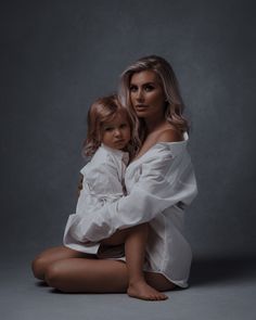 a woman sitting on the ground holding a small child in her lap and posing for a photo