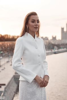 a woman in a white suit standing by the water