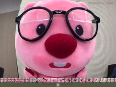 a pink stuffed animal with glasses on it's face and nose is looking at the camera