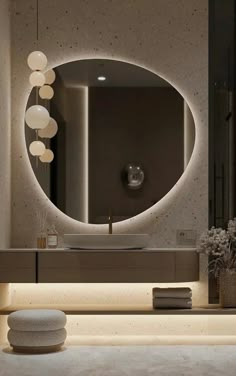 a bathroom with a large round mirror and lights on the wall above it's sink