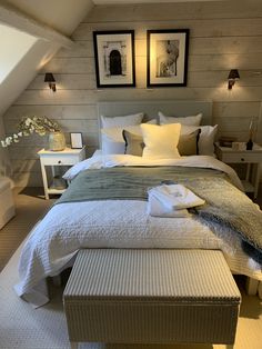 a bed with white linens and pillows in a bedroom next to two pictures on the wall