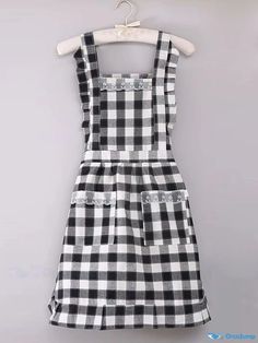 a black and white checkered dress hanging on a hanger in front of a gray wall