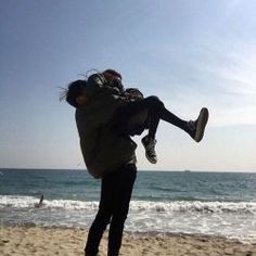 a man carrying a woman on his back while standing on top of a sandy beach