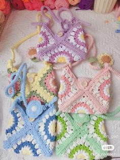 four crocheted purses sitting on top of a white table next to colorful balls of yarn