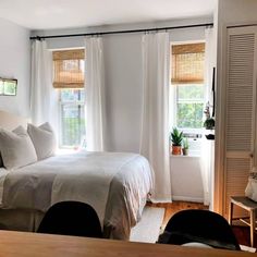 a bed sitting in a bedroom next to two windows