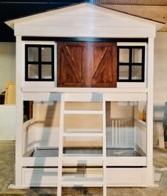 a white bunk bed with wooden doors and windows