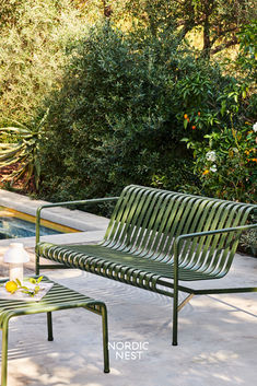 a green bench sitting next to a swimming pool