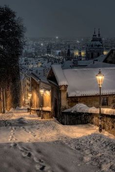 snow covered streets and buildings in the city at night with street lights lite up