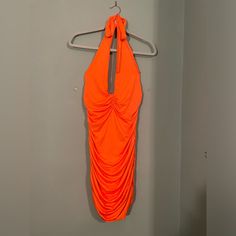 an orange dress hanging on a hanger next to a white wall in a bathroom