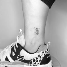 a woman's foot with a small snake tattoo on her left ankle and an animal print shoelace