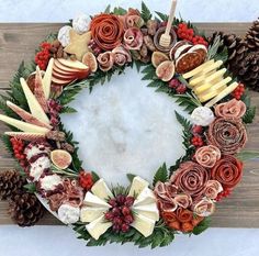 a wreath made out of different types of fruits and vegetables with pine cones on top