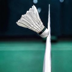 a badminton racket with five white shuttles on it's tip and the net in the background