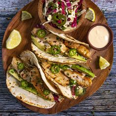 fish tacos with cole slaw and salsa on a wooden platter next to lime wedges