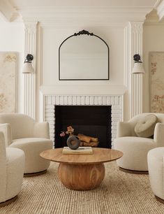 a living room with white chairs and a fire place