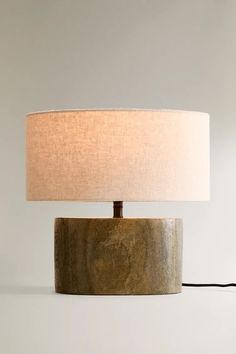 a table lamp with a white shade on it and a black cord plugged into the base