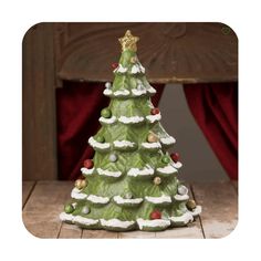 a small green christmas tree sitting on top of a wooden table