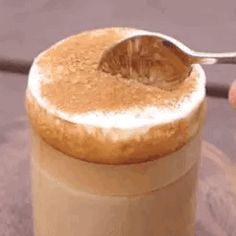 a person holding a spoon over a jar filled with liquid