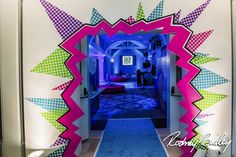 an entrance way to a bedroom decorated in bright colors and shapes with people standing on the bed