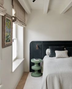 a bedroom with a bed, nightstand and window in the corner on the side wall