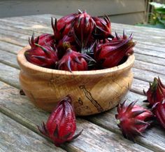 a wooden bowl filled with red flowers on top of a table