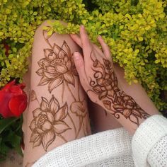 a woman's legs covered in hendix with flowers around her and hands resting on the ground