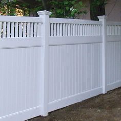 a white picket fence in front of a house with a dog on the ground next to it