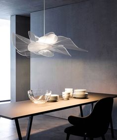 a dining room table with plates and bowls on it in front of a light fixture