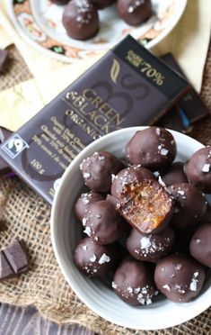 a bowl filled with chocolate covered donuts next to a book and some other items