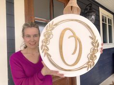 a woman holding up a sign with the letter o on it in front of a house