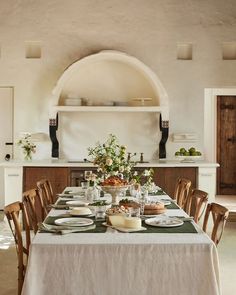 a dining table is set with plates and cups on it in front of an oven