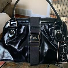 Nwt Jessica Simpson Black Patent Shoulder Bag. Never Used, Silver Hardware. Front Closing Clasp With Magnetic Closure At The Top Of The Bag. 2 Internal Zip Closure Pockets. Silver 4 Corner Bottom Protection Circles. Measures 13” In Length / 4.5” Width /. 16” Total Height Including Shoulder Handles /. 9” Bag Height Without Handles. Trendy Black Satchel With Magnetic Closure, Black Tote Satchel With Magnetic Closure, Jessica Simpson Handbags, Black Handheld Bag With Silver-tone Hardware, Black Hobo Bag With Silver-tone Hardware, Tote Shape, Black Leather Shoulder Bag With Silver-tone Hardware, Vegan Purses, Black Nylon Shoulder Bag With Silver-tone Hardware, Faux Leather Bag