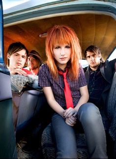 a group of young people sitting in the back of a van with one woman wearing a red tie