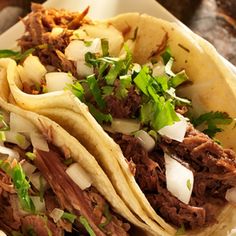 three tacos with meat, onions and cilantro sitting on a white plate