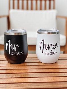 two black and white wine glasses sitting on top of a wooden table next to each other