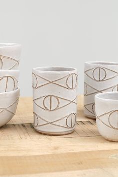 five white cups sitting on top of a wooden table next to each other with lines drawn across them