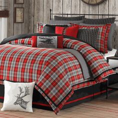 a bed with red and black plaid comforter in front of a clock on the wall