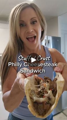 a woman holding up a sandwich in her hand with the caption, stuff crust philly cheesesteak sandwich