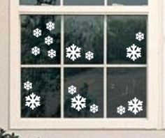 snowflakes are seen in the window of a house that is decorated with white paint