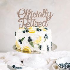 a white cake with blueberries and lemons on top is sitting on a table