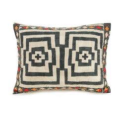 a black and white pillow with geometric designs on the front, sitting on a white surface