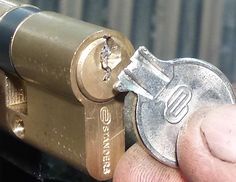 a person holding a coin in front of a lock on a metal object with one hand