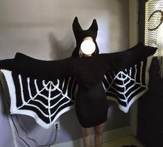 a woman wearing a black and white crocheted bat costume with spider webs on it