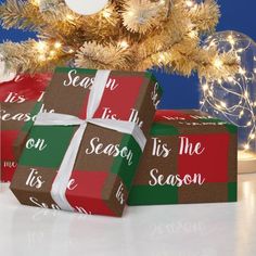 two presents wrapped in brown and green paper with white ribbon are sitting under a christmas tree