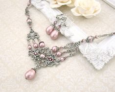 "To make this Victorian inspired necklace, I paired soft, powder pink Swarovski crystal pearls and beads with lovely, antique silver filigree with an elegant floral motif. I embellished the filigree with glinting Swarovski crystal stones and dressed the pearls in antique silver floral bead caps and adornments to enhance the vintage feel. The crystal beads are Swarovski's Antique Pink hue - an elegant dusty pink that to me, has a romantic Old-World feel. ------------------------------------------ Elegant Pink Necklace With Intricate Design, Feminine Silver Pearl Necklace For Wedding, Feminine Pink Pearl Necklace For Wedding, Elegant Pink Beaded Pearl Necklace, Ornate Pink Wedding Jewelry, Elegant Pink Beaded Bridal Necklace, Pink Pearl Wedding, Victorian Wedding Jewelry, Pearl Wedding Necklace